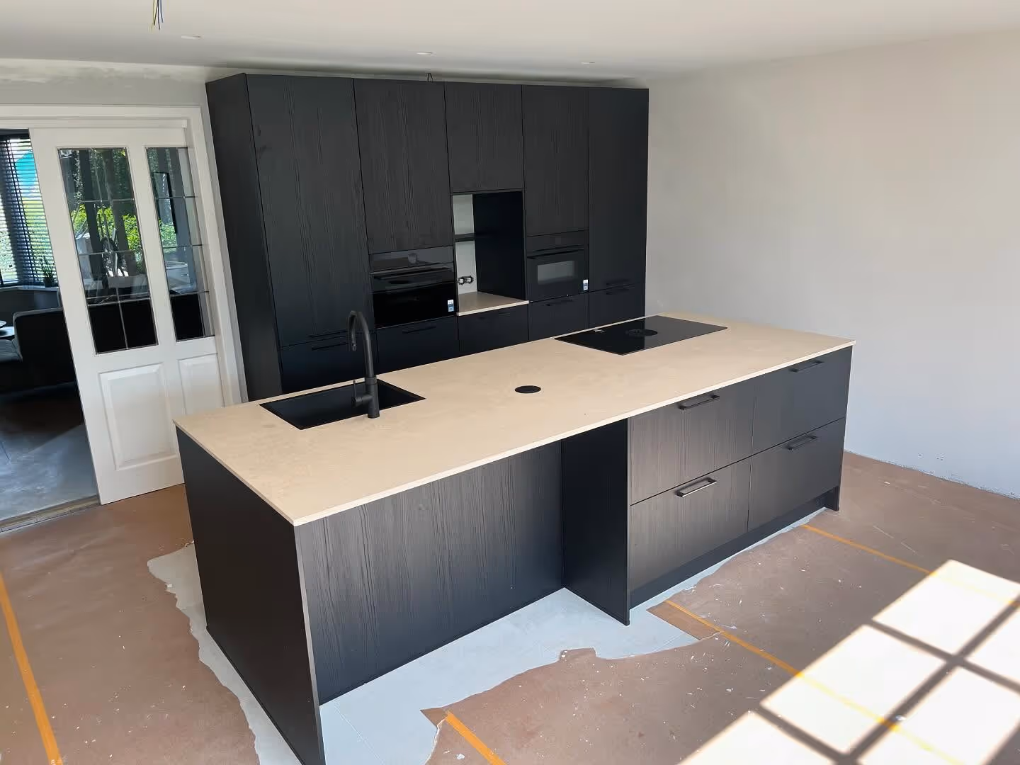 A bright dining room with a dark table, white chairs, a striped bench, a rug, and a gold chandelier