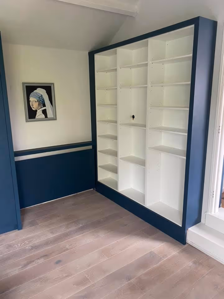 A minimalist home office with a desk, chair, computer, and a large plant.